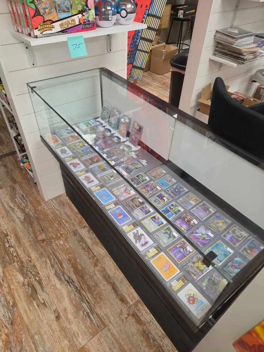 Display case of graded Pokémon cards with Poké Ball tins and pin collections above